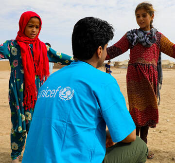 Nos quedamos para proteger a la infancia Niñas hablando con un miembro del staff UNICEF