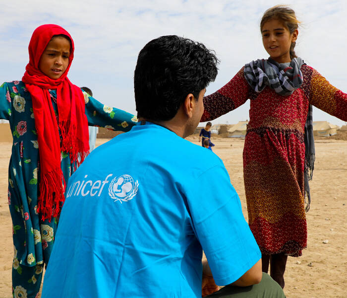 Nos quedamos para proteger a la infancia Niñas hablando con un miembro del staff de UNICEF