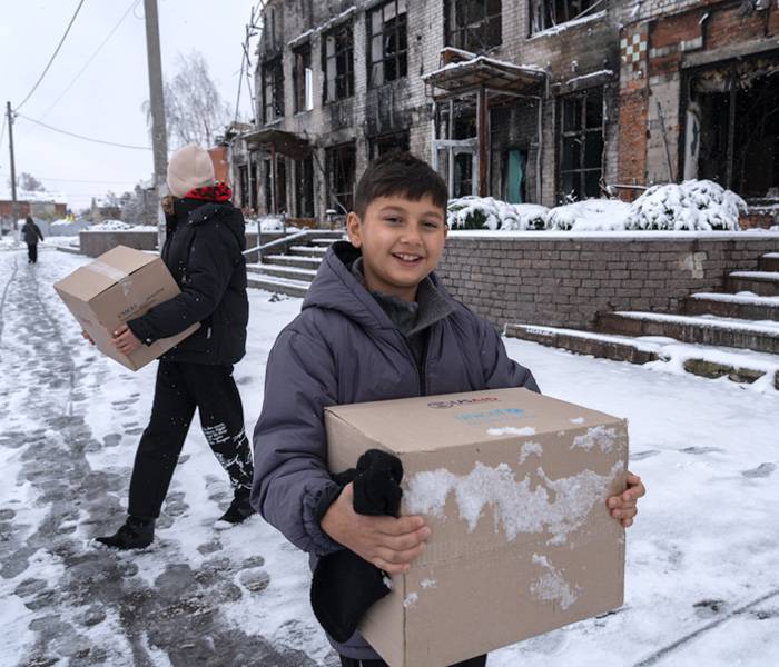 Artur lleva una caja con ropa de invierno, recibida en el punto de distribución de UNICEF. Artur de 9 años