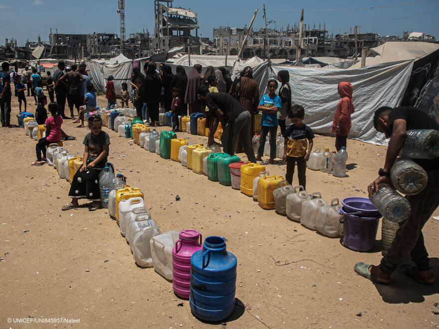 Los niños esperan en fila en un punto de distribución de agua apoyado por UNICEF en el campamento de Al-Mushtal, en el barrio de Al Rimal de la ciudad de Gaza, el 11 de agosto de 2025 UNI845957