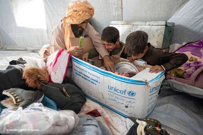 Una familia afgana abre una caja de suministros de UNICEF