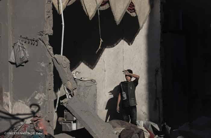 Un niño palestino alza la vista rodeado de los escombros provocados por la guerra