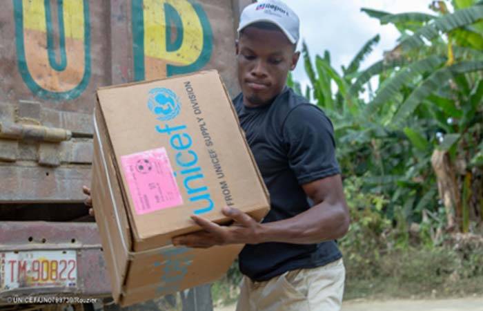 Unas niñas de Haití abren ilusionadas sus libros escolares de UNICEF en la escuela
