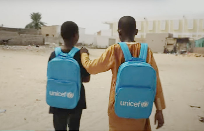 Dos niños mauritanos llevan a sus espaldas mochilas azules de UNICEF