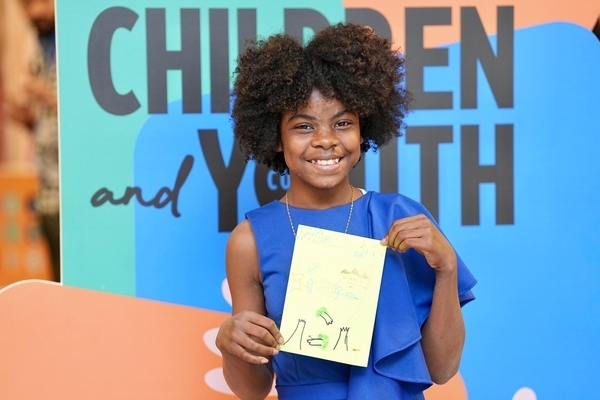 Una niña posa en la COP28 con un dibujo