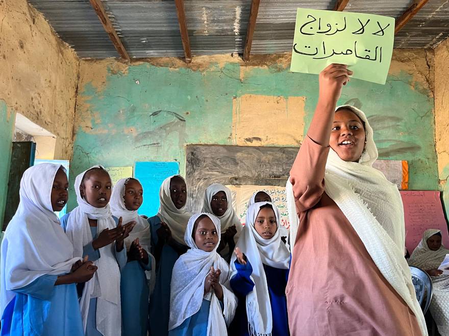 Una de las activistas del club sostiene un cartel que pone: “No al matrimonio infantil”. Un grupo de niñas en el aula
