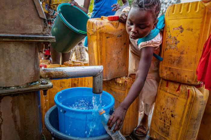 Una niña recoge agua limpia en República Centroafricana.