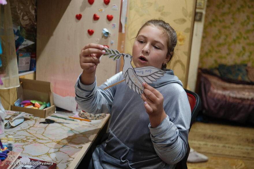 Maria-Vitalina dibuja una paloma de la paz de papel con la inscripción "Traer la paz a Ucrania" desde el refugio de la familia, en el sótano de la casa.