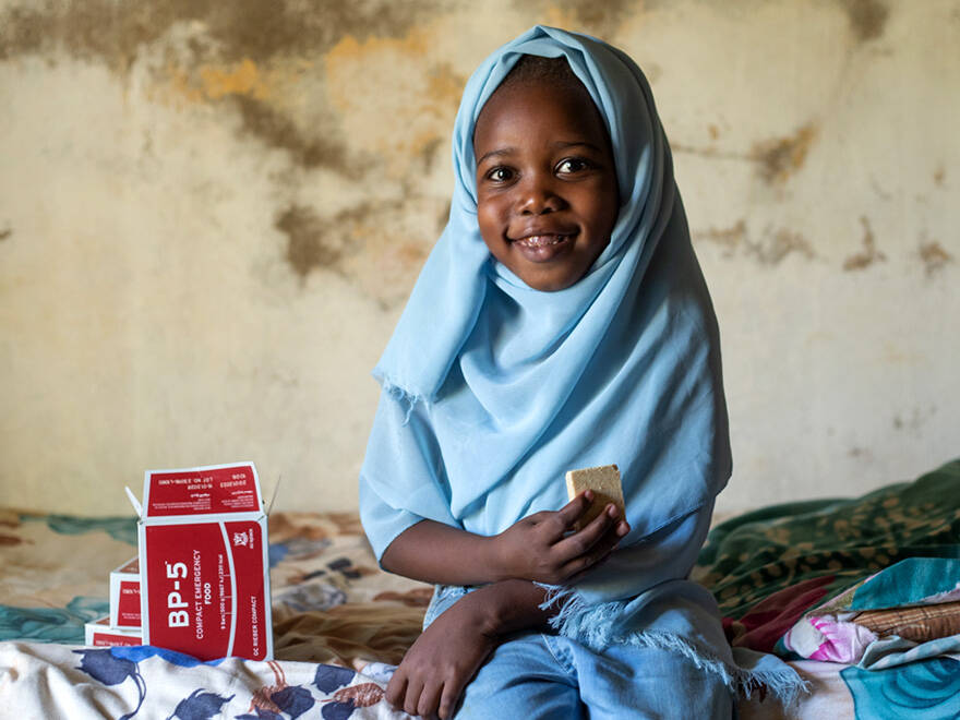 Una niña come galletas enriquecidas a base de cereales distribuidas por UNICEF para combatir la desnutrición. Imagen de una niña