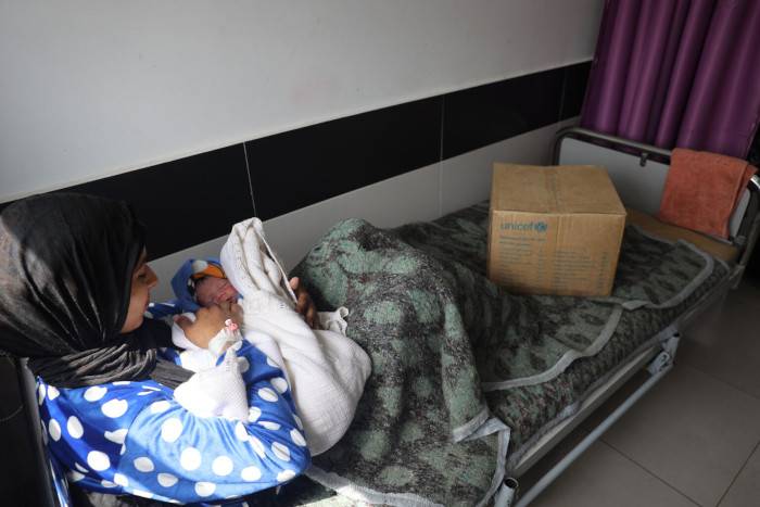 Una madre recibe ropa para su bebé en Gaza.