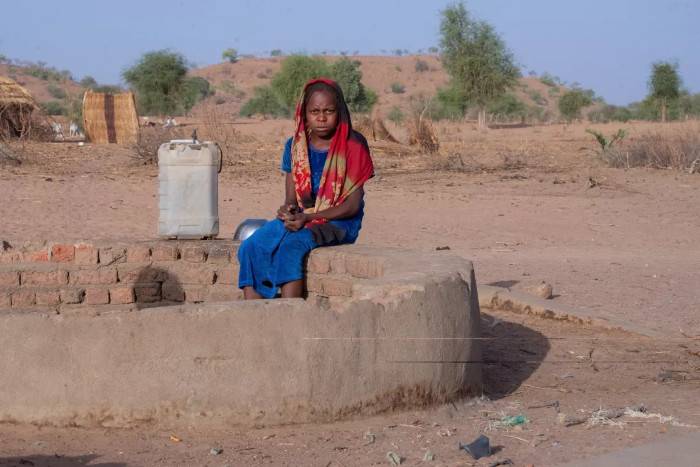 Mayada delante del pozo de agua.