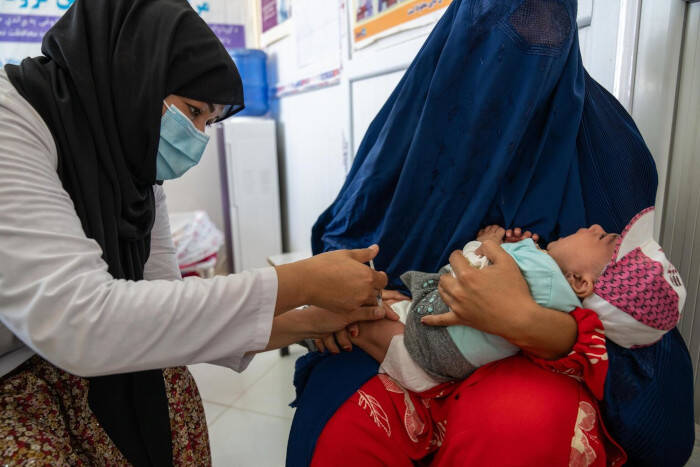 Una trabajadora de la salud vacunando a un bebé en Afganistán.