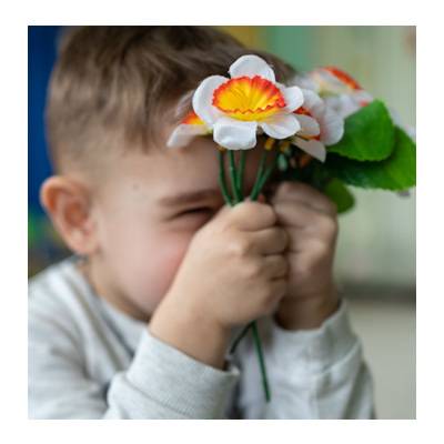 Un niño juega con unas flores Un niño juega con unas flores