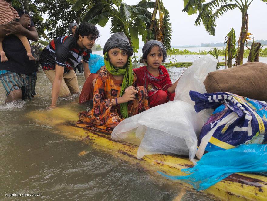 Niños atraviesan las aguas de la inundación en una balsa improvisada, en busca de refugio, en Feni.