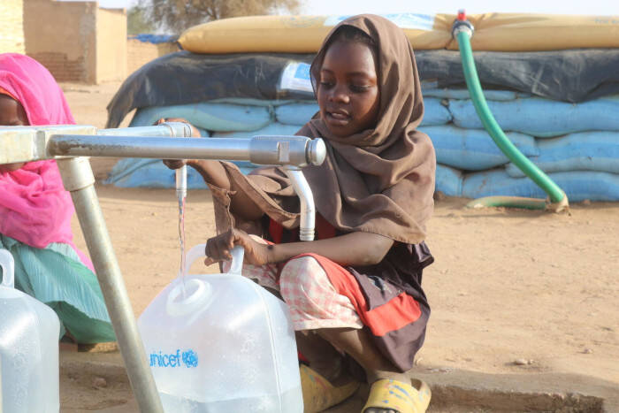 Niños desplazados recogen agua de un punto de abastecimiento instalado por UNICEF en Darfur del Norte.
