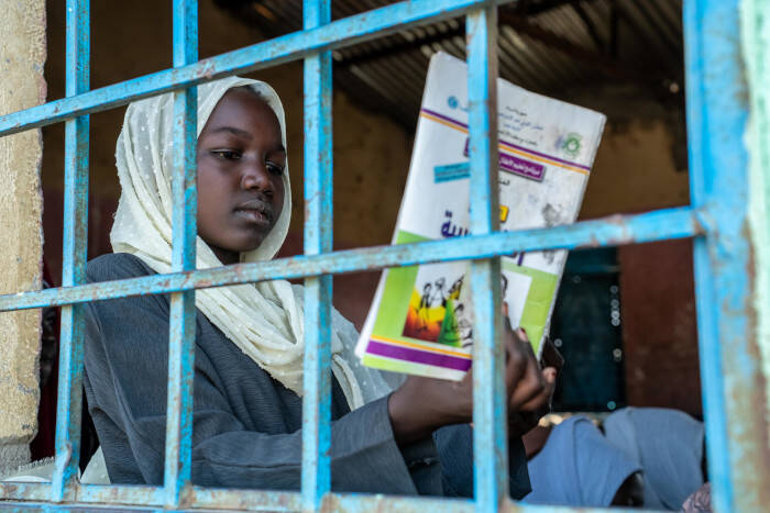Una niña leyendo un libro en un espacio apoyado por UNICEF.