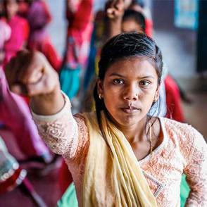 Una adolescente levanta el brazo