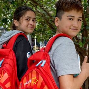 Dos niños con mochilas escolares