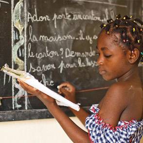 Una niña con un cuaderno de frente de una pizarra