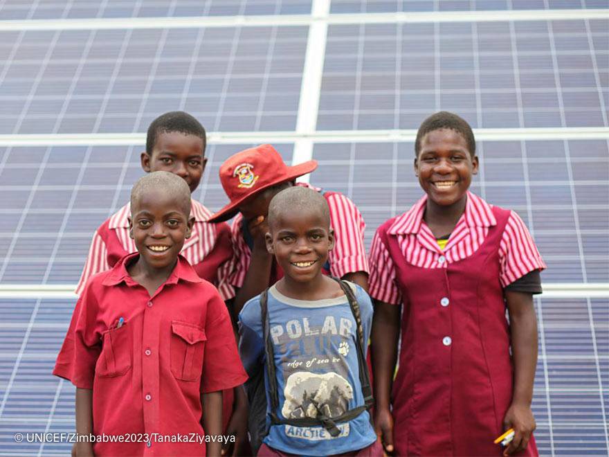 Niños frente a una placa solar.