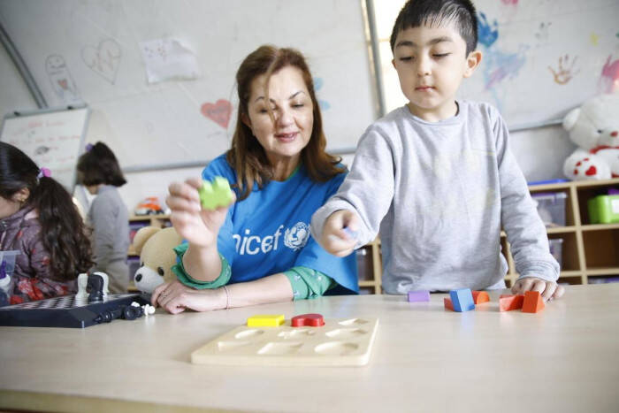 Una trabajadora de UNICEF juega con un niño en un espacio amigo de la infancia.