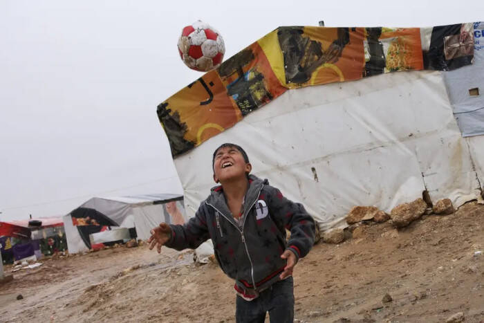 Un niño practica con su balón cerca de la tienda de campaña de su familia, en Líbano.