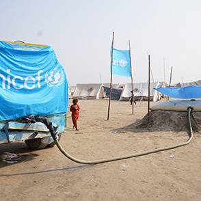 Un camión cisterna de UNICEF abastece un tanque plegable en una localidad desértica