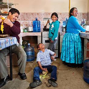 Una familia sonríe mientras prepara la comida en su cocina