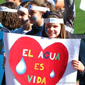 Campaña escolar Una niña muestra sonriente una pancarta en la carrera de Gotas de su colegio