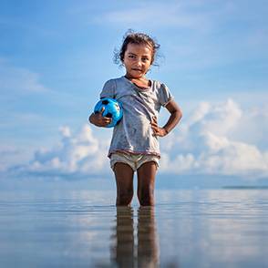 Derecho al agua y el medioambiente Una niña con una pelota en una laguna